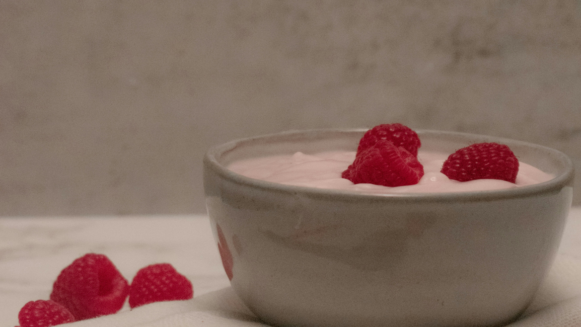 image of a bowl with the raspberry smoothie mix with raspberries on top. with three raspberries at the side.