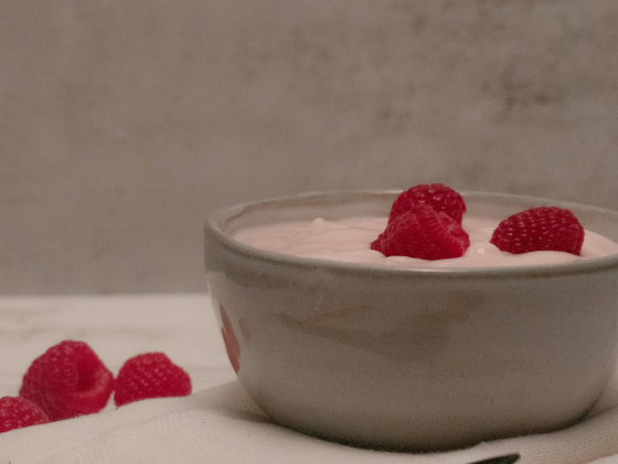 image of a bowl with the raspberry smoothie mix with raspberries on top. with three raspberries at the side.