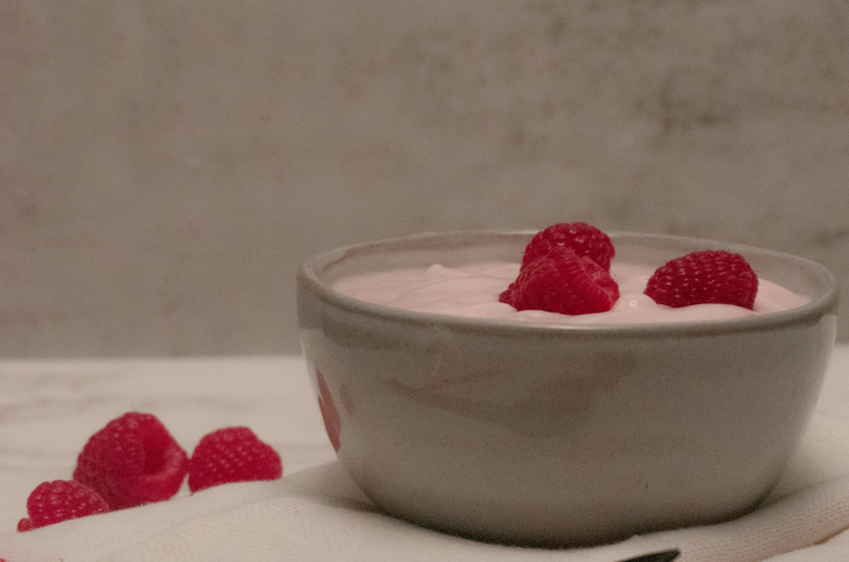 image of a bowl with the raspberry smoothie mix with raspberries on top. with three raspberries at the side.