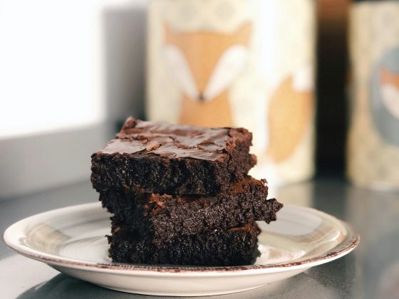 A medium close up shot of three stacked brownies on a plate.