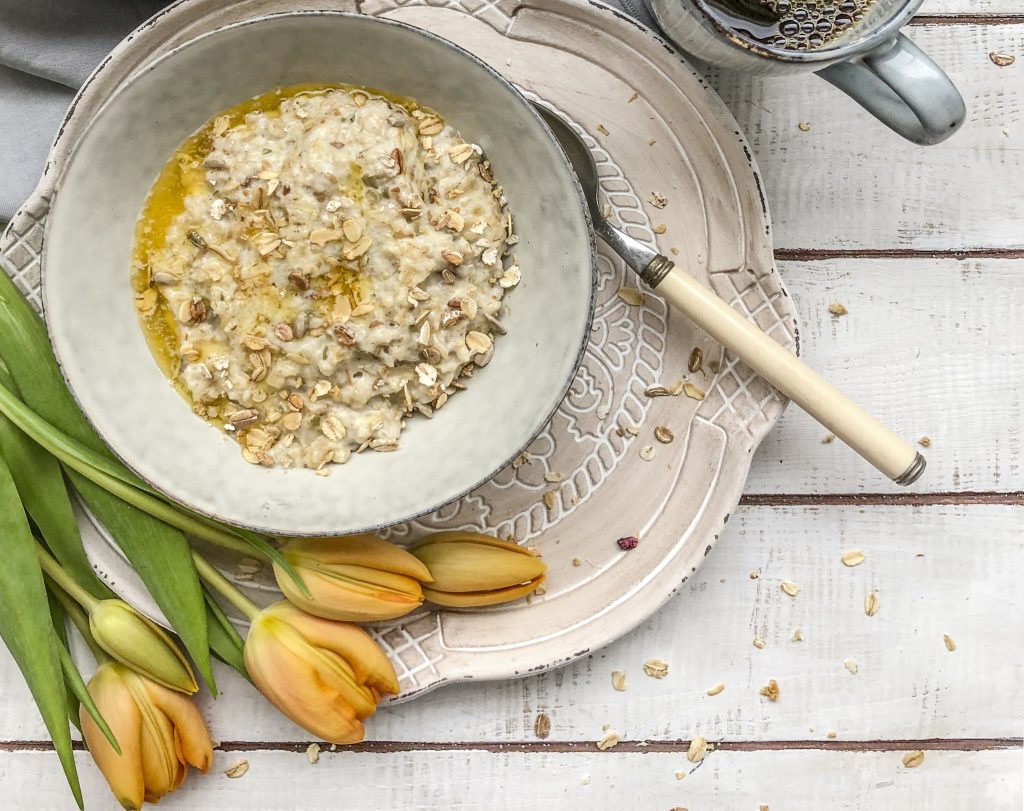 Egg protein porridge bowl. As part of our egg recipe guide. a medium shot of a porridge bowl, birds eye view, with yellow flowers curving around the bowl on the bottom left side.